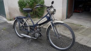 cyclomoteur_a_pedales_50cc_vintage_type_peugeot_bleu_dans_cour_francaise