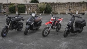 Photo Panasonic GH4 d’un comparatif 50cc 2026 avec moto 50cc, scooter 50cc, moto cross 50cc et scooter électrique en parking urbain