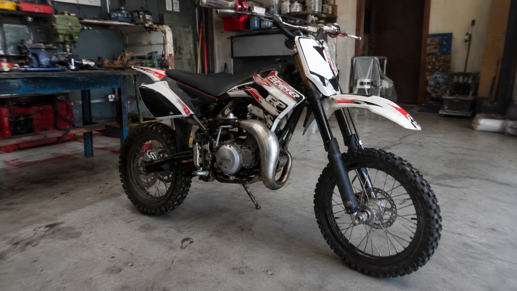 Beta 50cc rouge et blanche photographiée dans un atelier mécanique, avec moteur, échappement et roues tout-terrain visibles pour illustrer un avis sur la mécaboîte italienne.