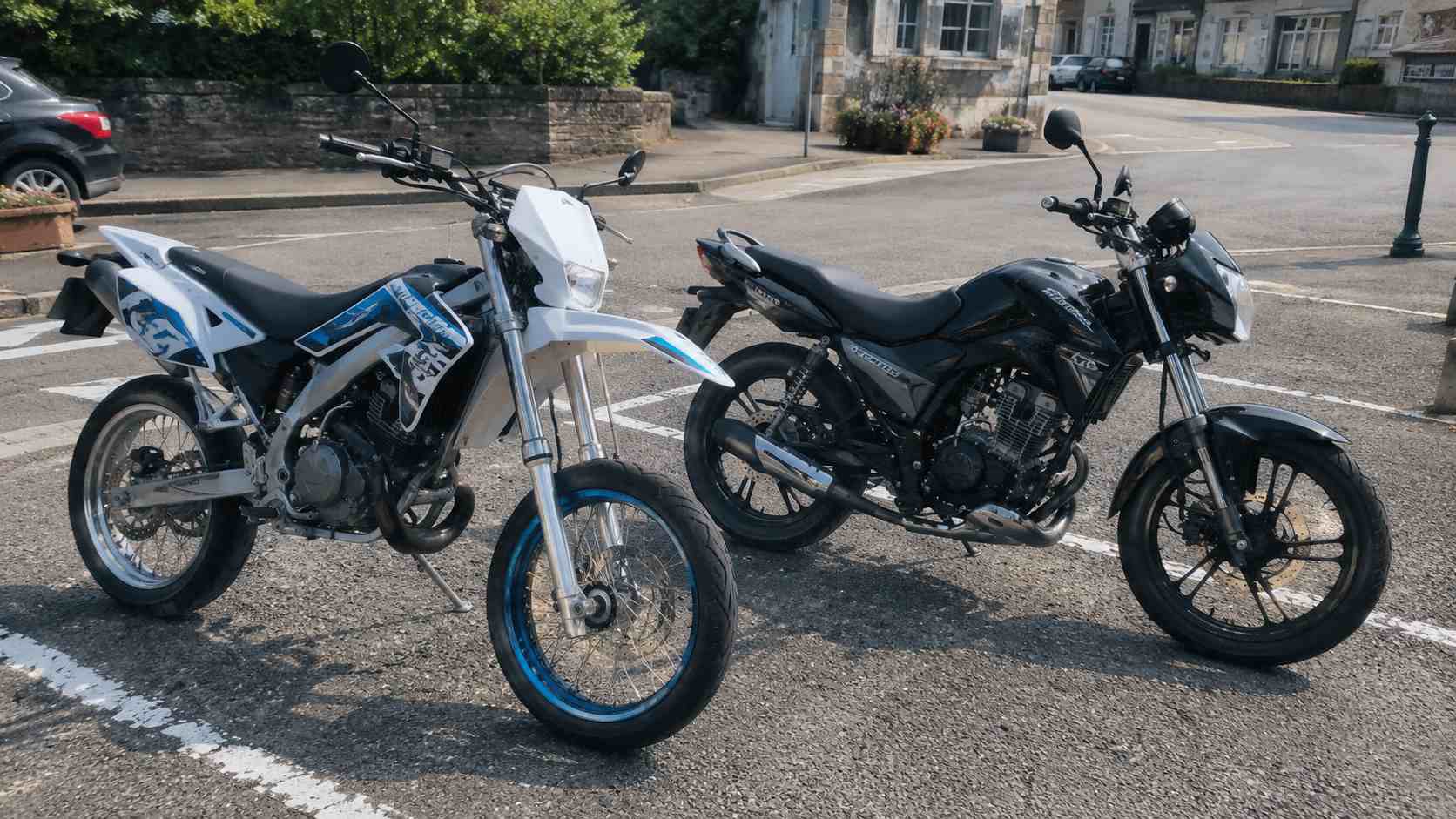 comparatif moto 50cc route supermotard clair et roadster noir stationnes sur bitume