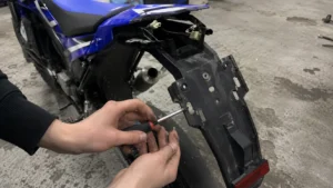 depose_garde_boue_arriere_noir_moto_enduro_bleue_blanche_tournevis_connecteurs_faisceau_catadioptre_atelier_30_juillet_2026_panoramique_1672x941
