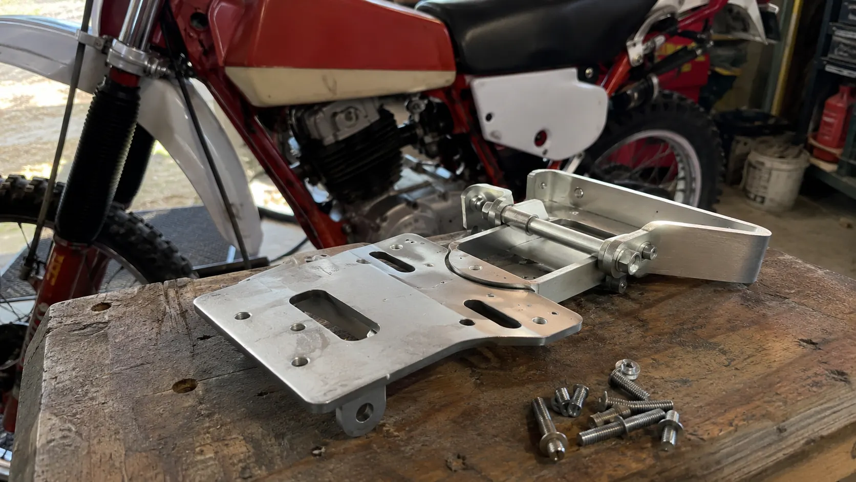support de plaque 50cc en aluminium avec visserie inox sur etabli devant moto enduro rouge et blanche