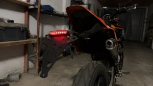support_plaque_immatriculation_noir_ajoure_feu_led_rouge_allume_supermotard_orange_garage_sombre_30_juillet_2026_panoramique_1672x941