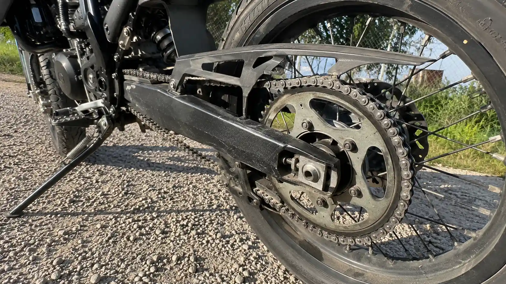 train_arriere_moto_50_bras_oscillant_noir_couronne_acier_chaine_tendeur_disque_frein_jante_rayons_contre_plongee_30_juillet_2026_panoramique_1672x941