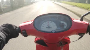 vue_subjective_compteur_scooter_piaggio_zip_rouge_cadran_80_kmh_jauge_carburant_main_gantee_route_contre_jour_30_juillet_2026_panoramique_1672x941