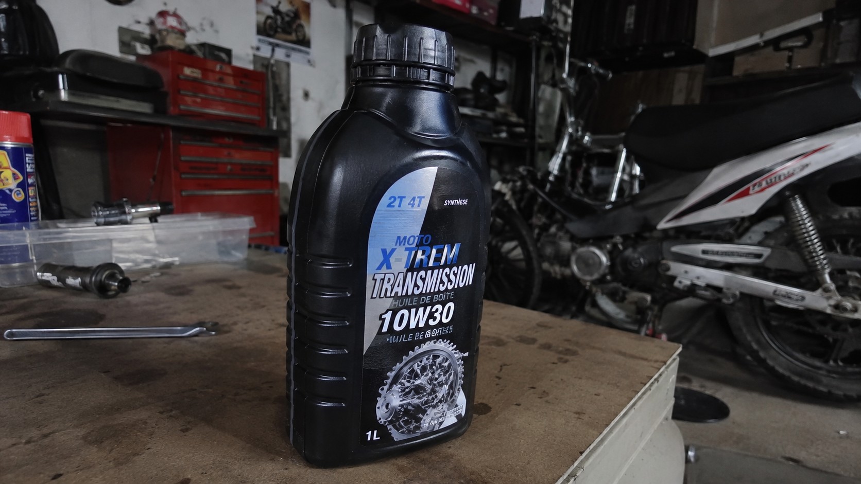 bidon_huile_de_boite_50cc_moto_x_trem_10w30_transmission_1_litre_pose_sur_etabli_garage_mecanique_moto_50cc_moteur_transmission_outils_ambiance_atelier_panasonic_gh4_2026