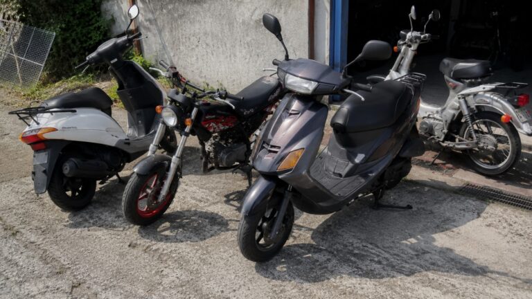 Scooters et motos 50cc Suzuki d'occasion exposés en extérieur au soleil