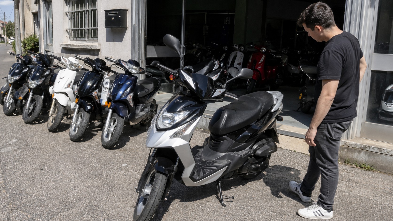 vitrine de magasin 50cc avec scooters exposés et client qui en inspecte un, pour comparer avec une ducati 50cc introuvable en neuf